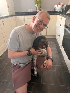 Dominic Knowles smiling with a dog in his arms.
