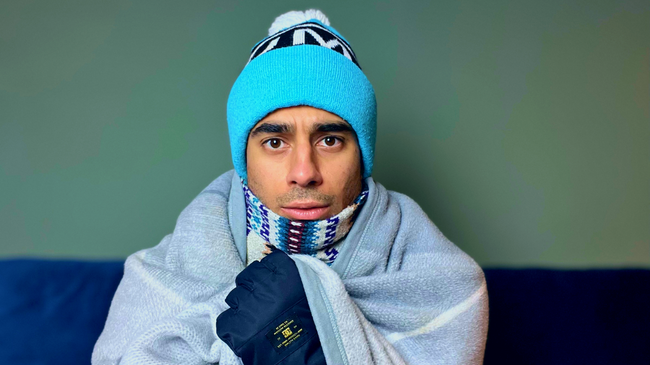 A photograph of a man in winter clothing looking cold